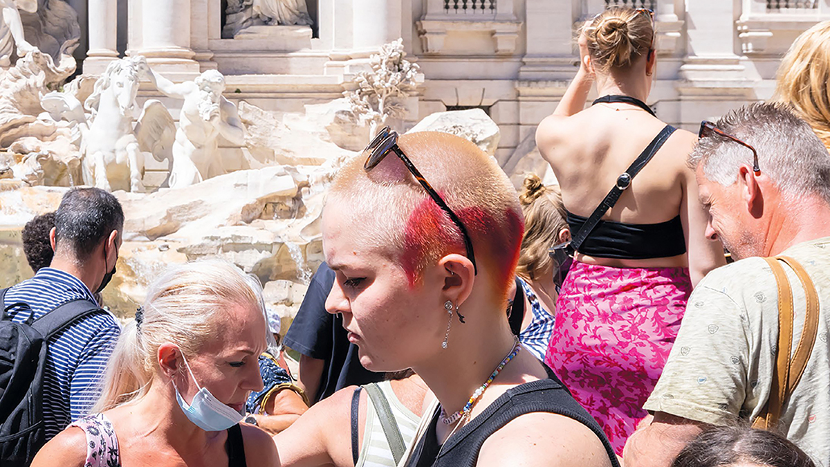 detail of a magazine cover showing a punk girl with light skin and others standing in front of the Trevi Fountain in Rome
