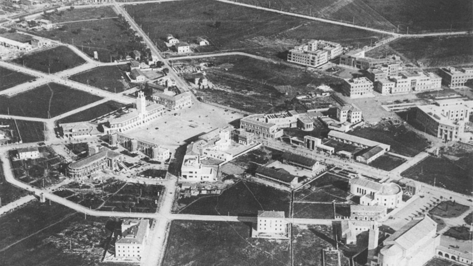 Black and white aerial photograph of the Italian city of Littoria, showing buildings, roads, and plazas