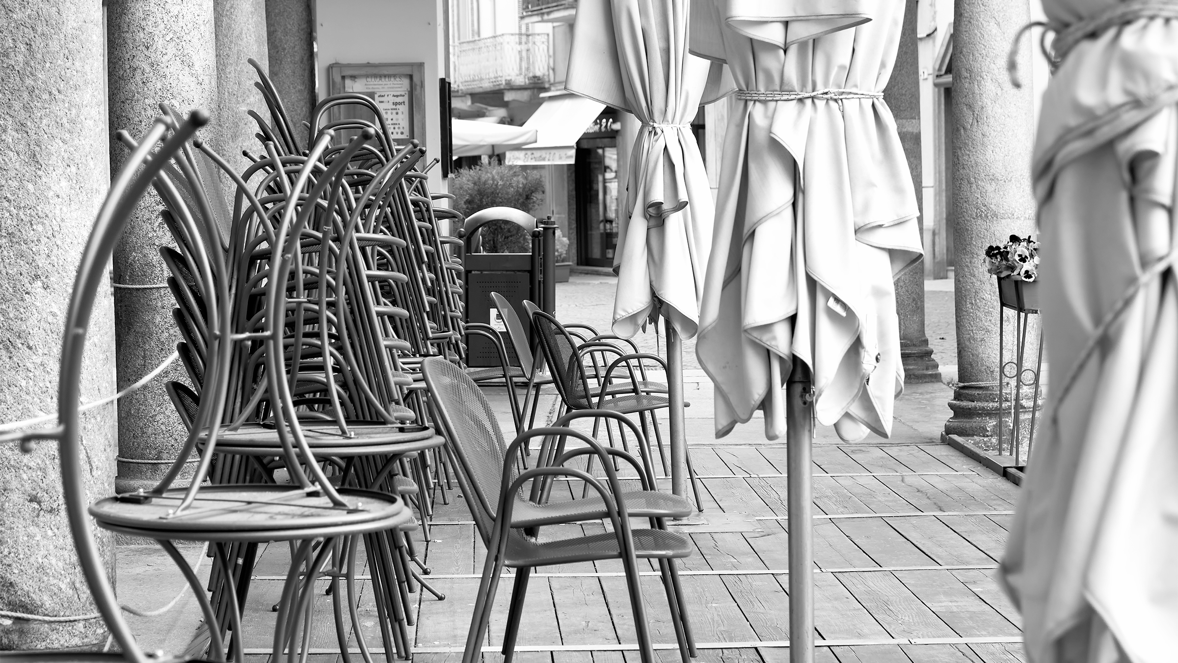 Frank Snowden COVID Black and white photograph of outdoor dining chairs stacked up on the sidewalk