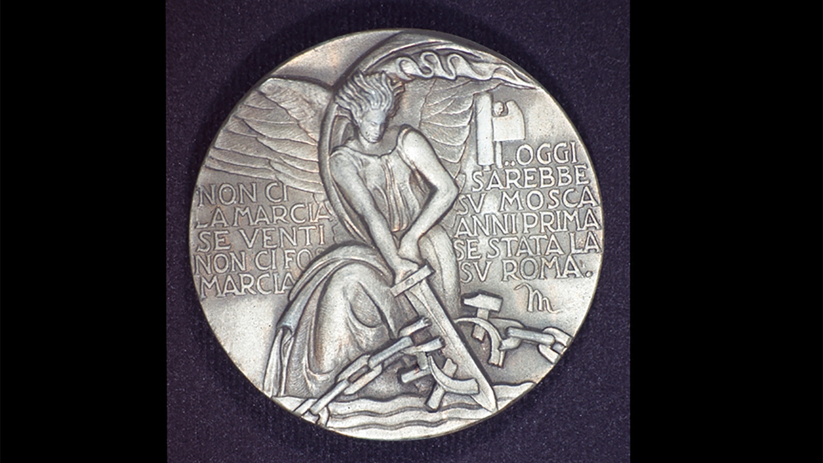 Marla Stone Lecture 2022 Silver colored round medallion with text and a winged woman breaking a chain with a sword