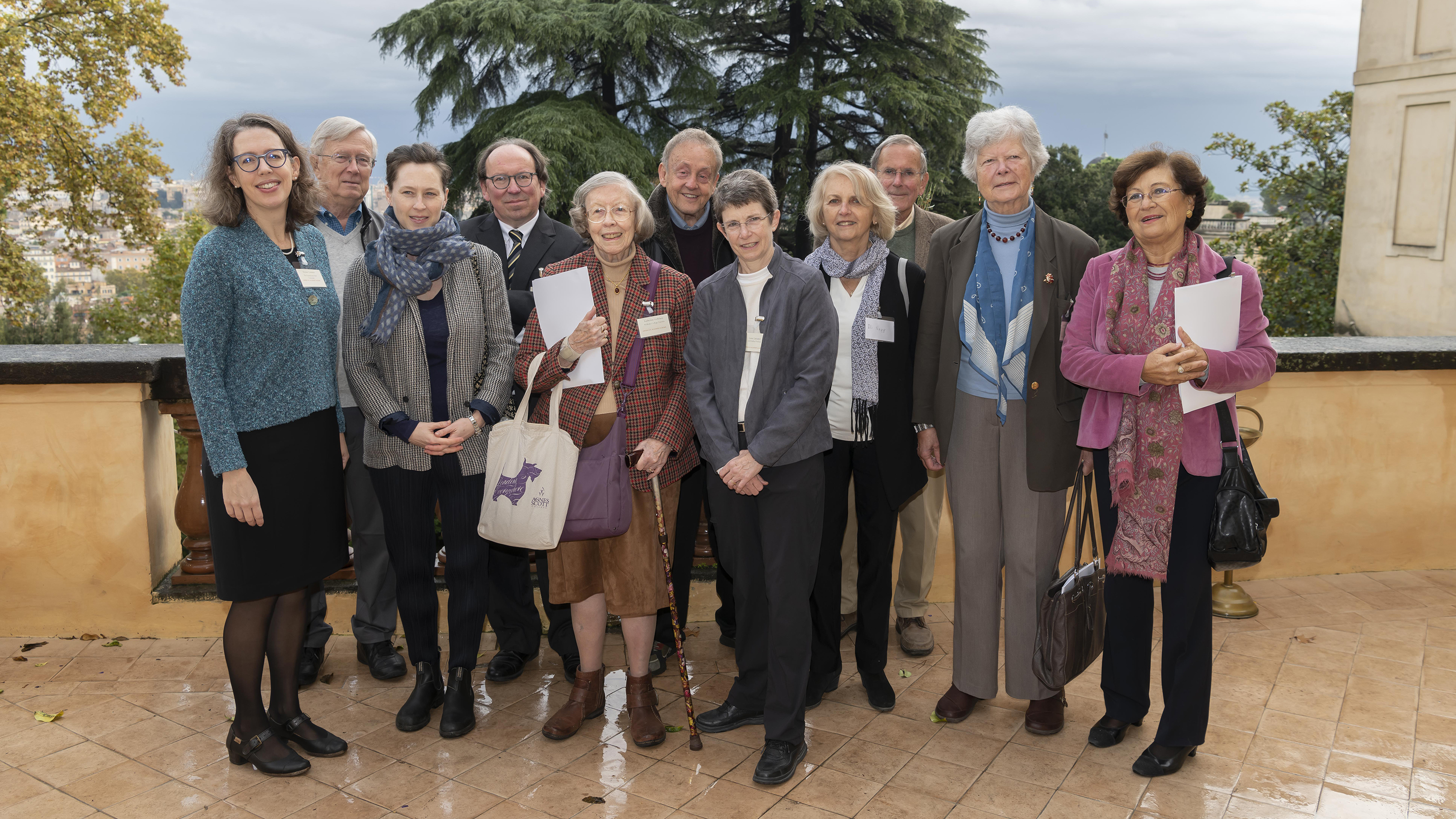 Color photograph of eleven men and women who spoke at the conference, standing in a row on an outdoor patio at the Academy