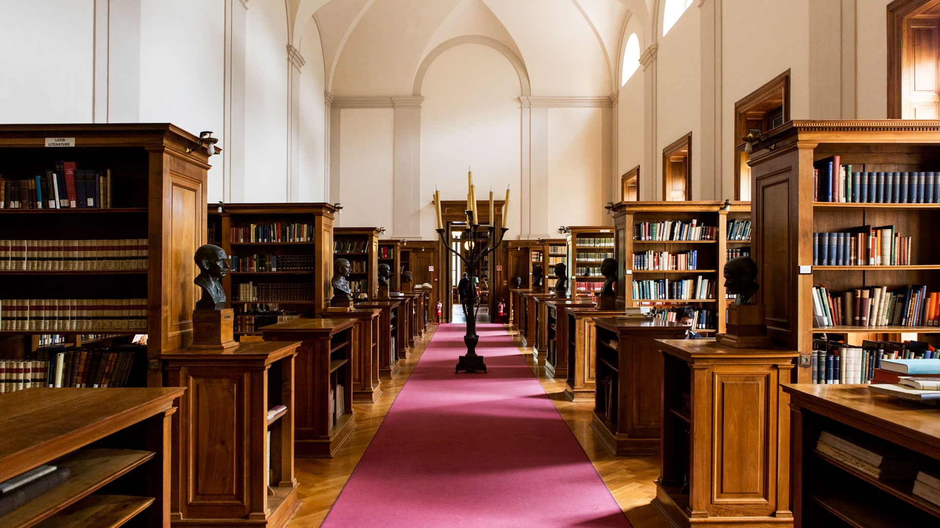 Color photograph of the Arthur Ross Reading Room showing bookcases, desks, and a candelabra sculpture in the central walkway