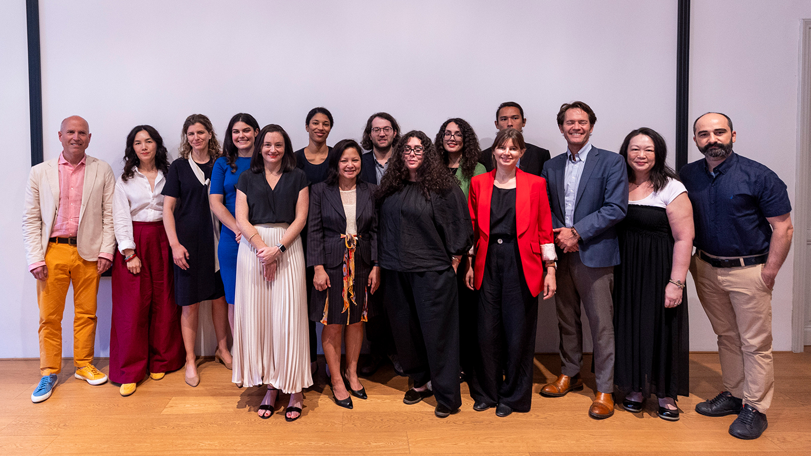 Color photo of fifteen people standing and posing for the camera in rows