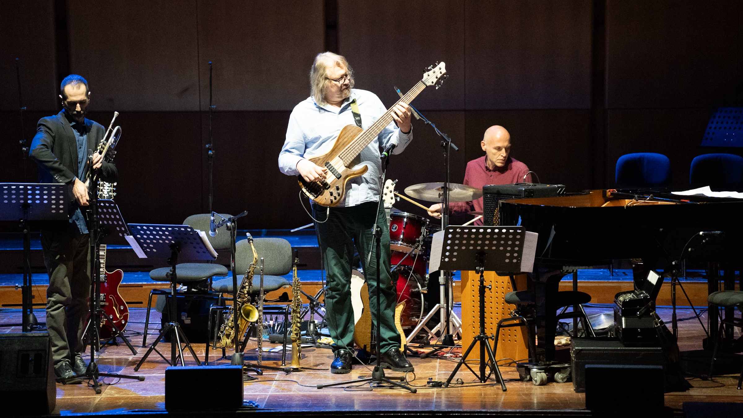 A man plays guitar on a stage, a band behind him