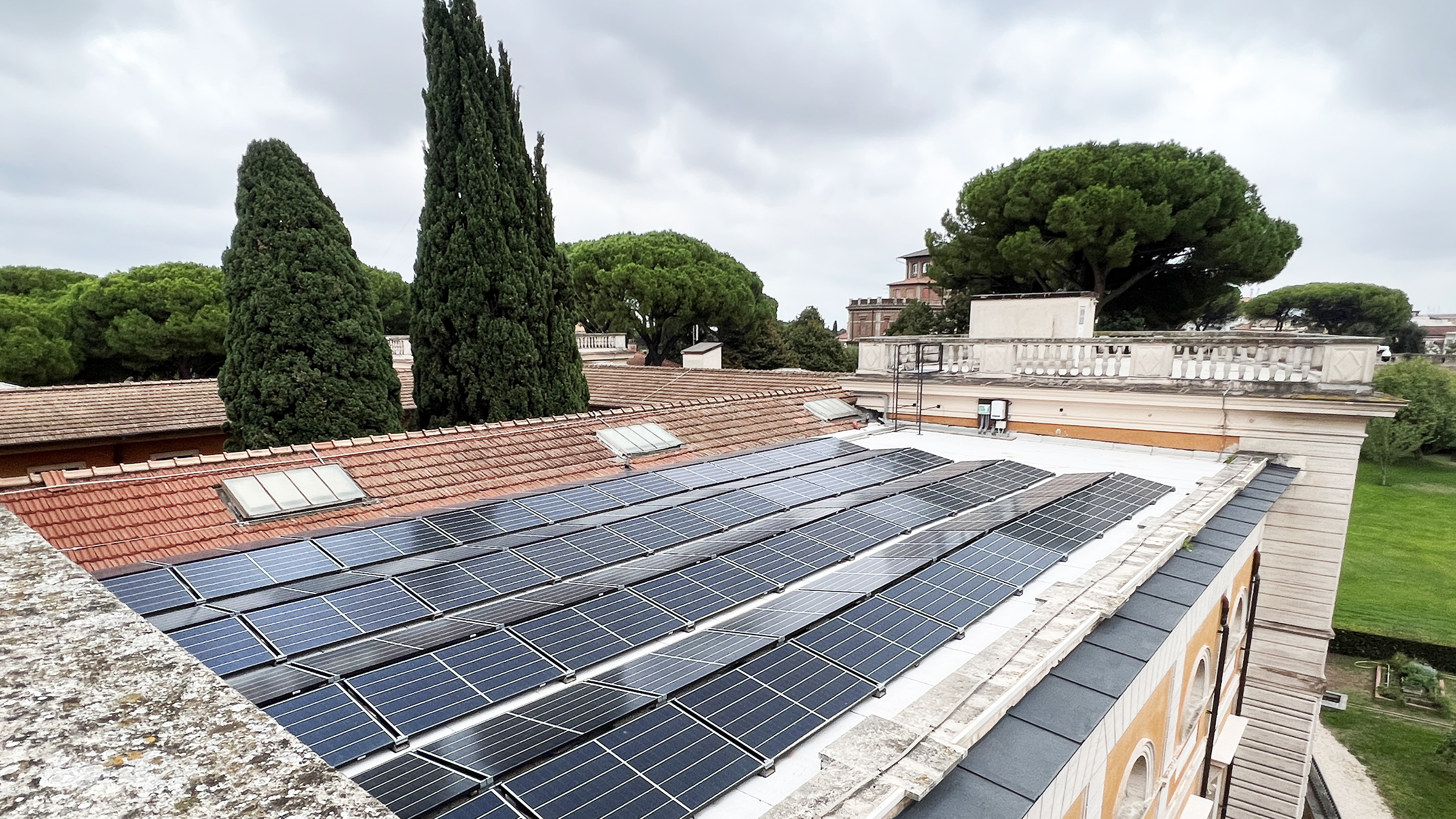 Color photographs of solar panels on a flat room, with the tops of trees in the background