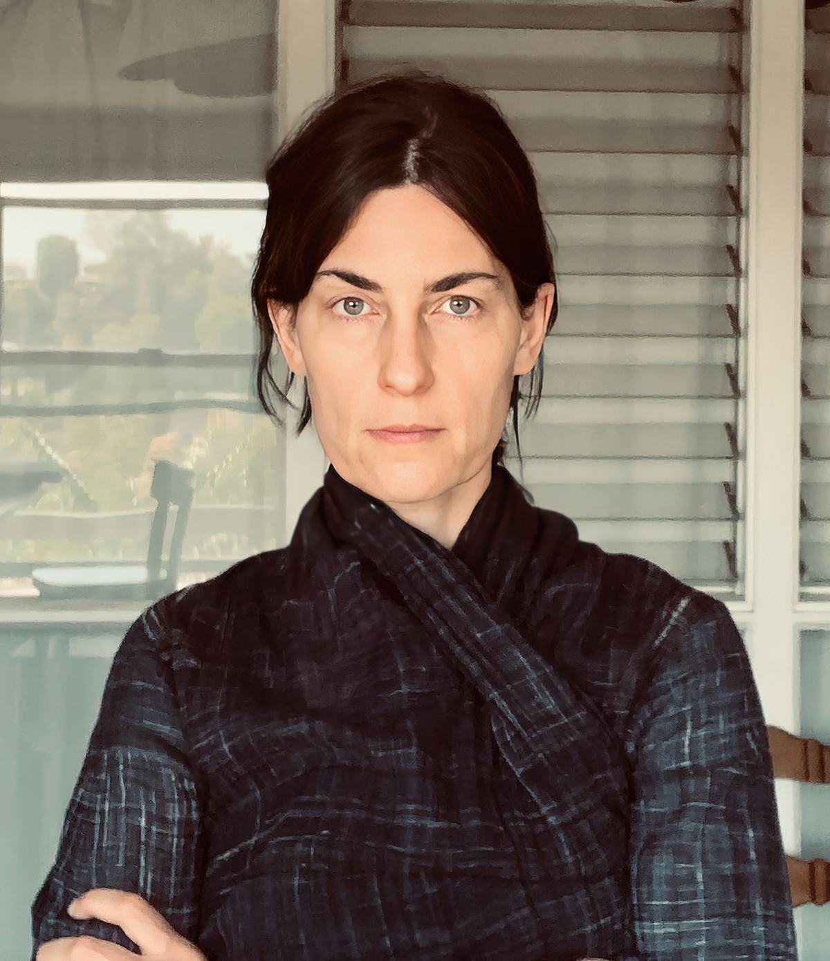 Amy Knight Powell Color photograph of the head and torse of a light skinned woman with brown hair looking directly at the camera with a serious face