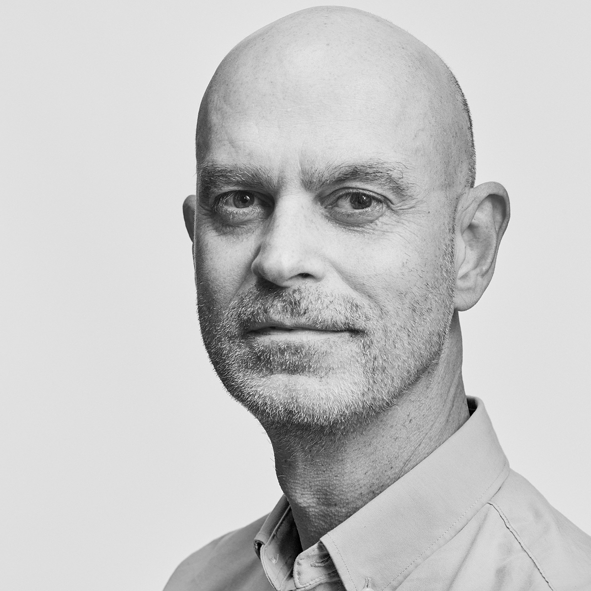 Arturo Herrera Black and white photograph of the head of a light skinned man wearing a collared shirt and looking directly at the camera with a serious face