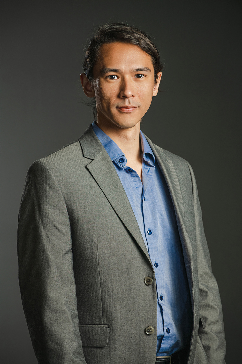 Christopher Erdman Color photograph of an Asian man wearing a blue shirt and blazer looking at the camera