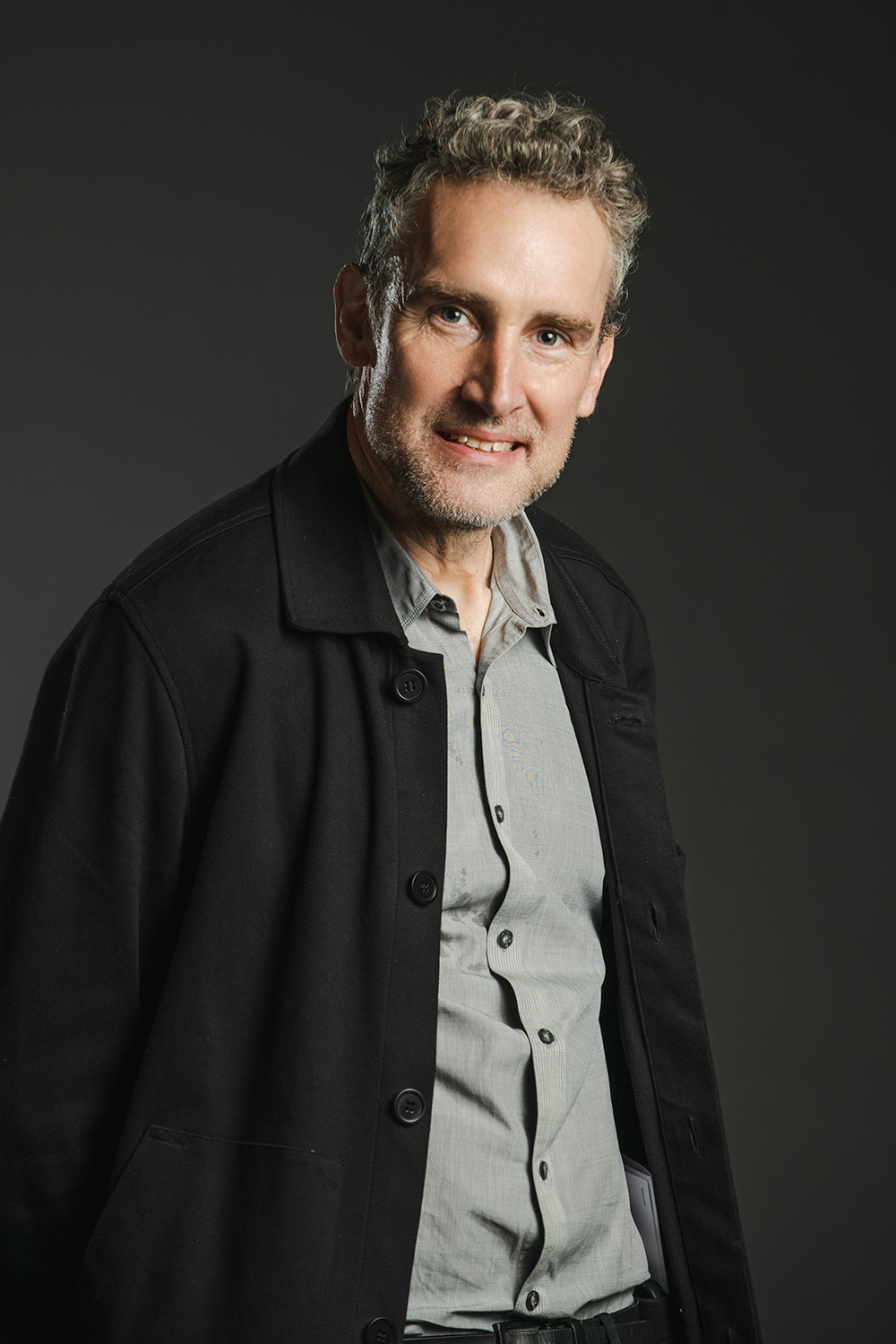 David Weeks Color photograph of a light skinned man wearing a dark jacket over a button up shirt