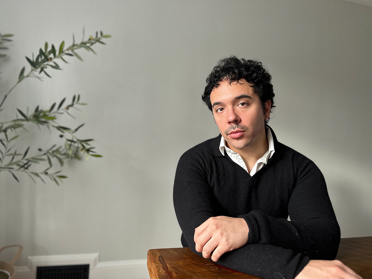 Lucas R. Ramos Color photograph of a man seated at the desk looking at the camera