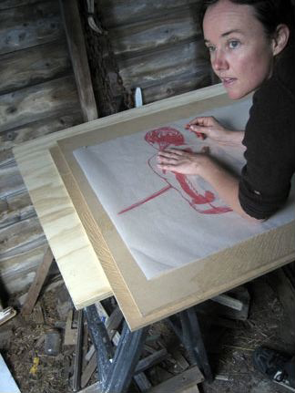 Marie Lorenz Color photograph of the head and shoulder of a light skinned woman working at a drafting table, with a drawing in front of her; she looks to the left offscreen