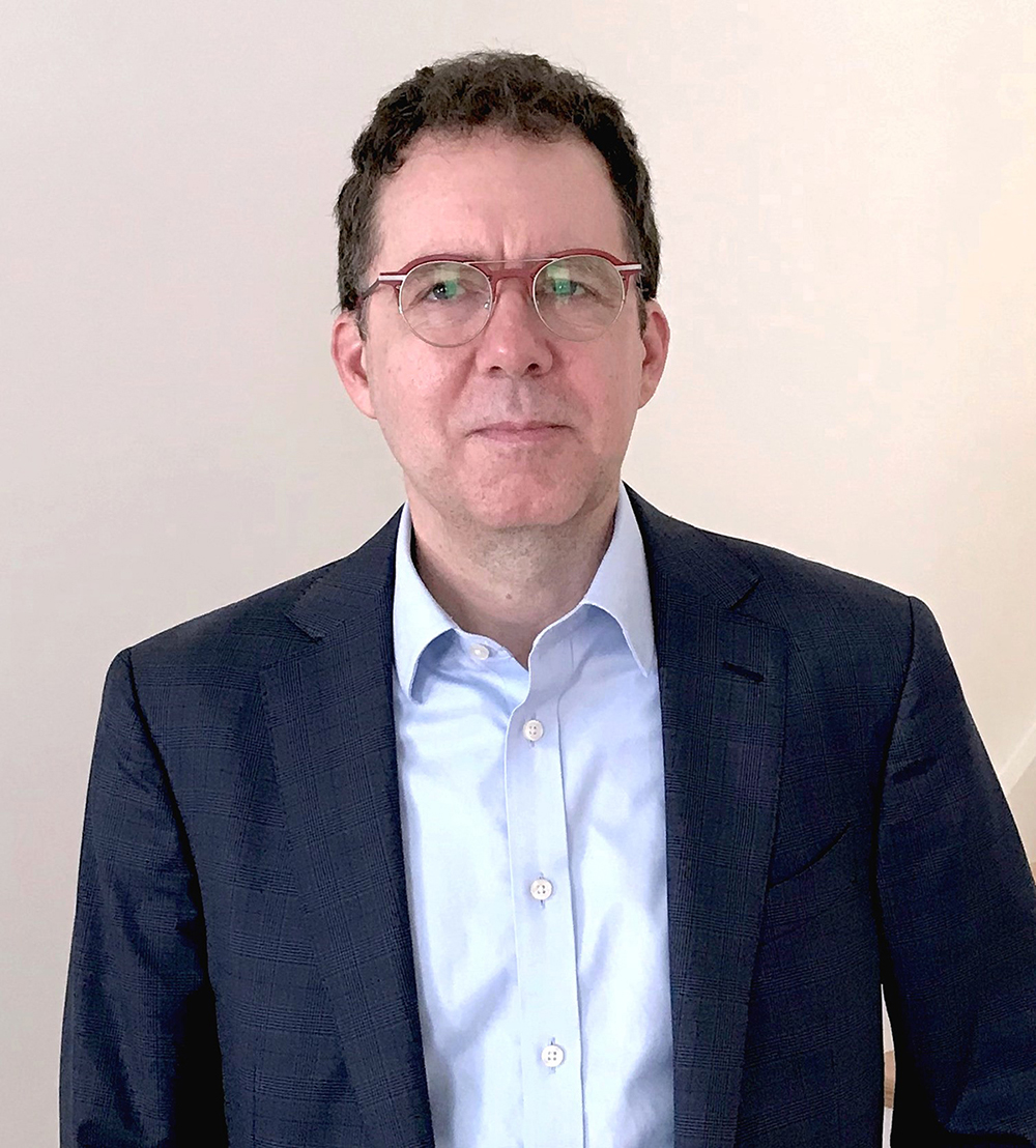 Michael Lee Color photograph of the head and torso of Michael Lee wearing a suit jacket and standing in front of a white wall