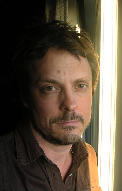 Richard Wittman Color photograph of the head and shoulders of a light skinned man with a beard and a pensive look on his face