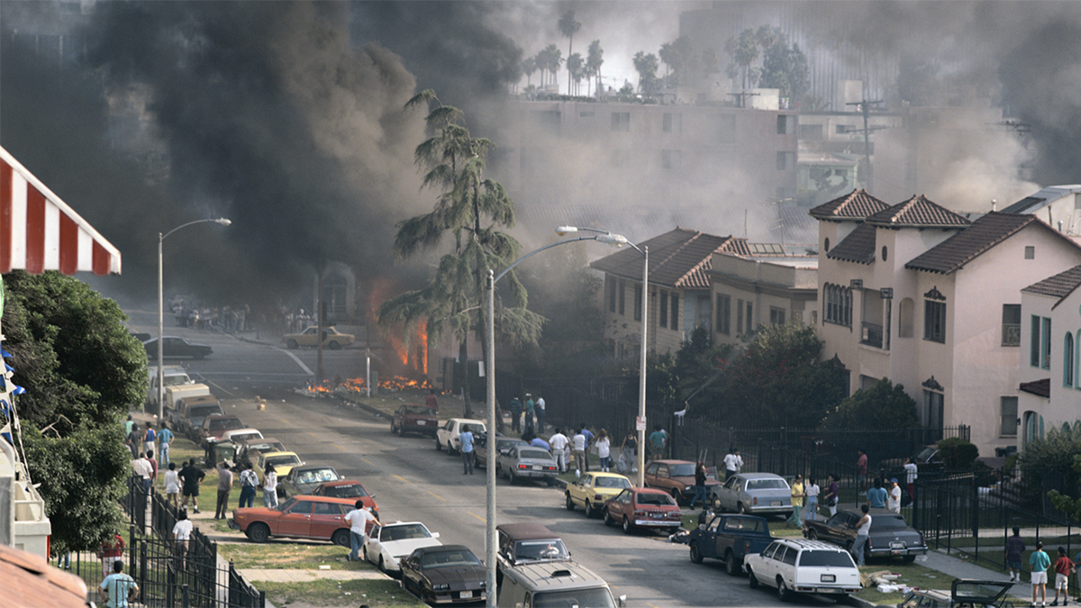 Color photograph of fire and smoke in a black neighborhood during the 1992 uprising in Los Angeles