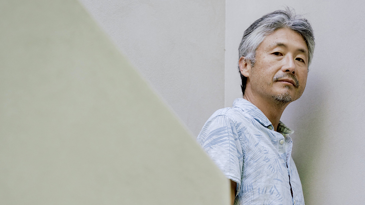 Color photograph of Chang-Rae Lee's head and torso as he stands on the landing of a stairwell