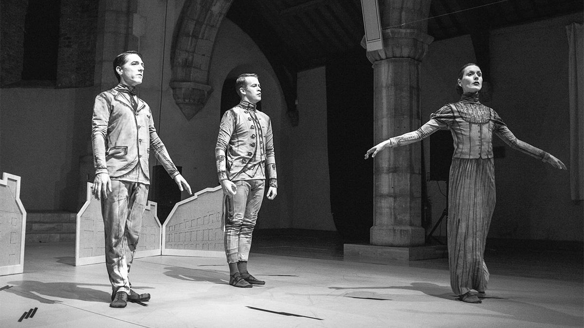 Black and white photo of three perfomers in costume on a stage