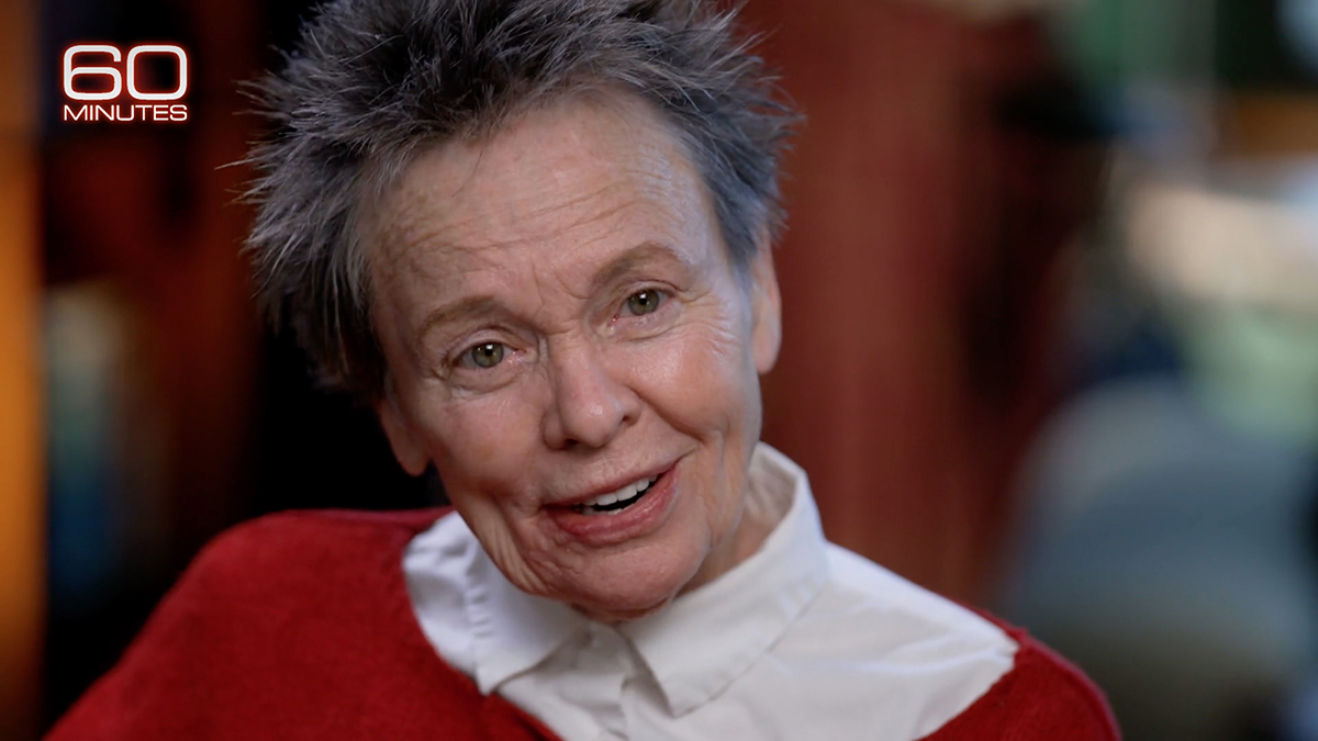 Screenshot of a television interview with a closeup of the head and shoulders of Laurie Anderson talking to a person off camera