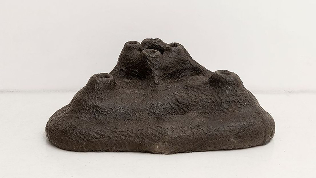 Color photograph of a sculpture that looks like a volcanic rock
