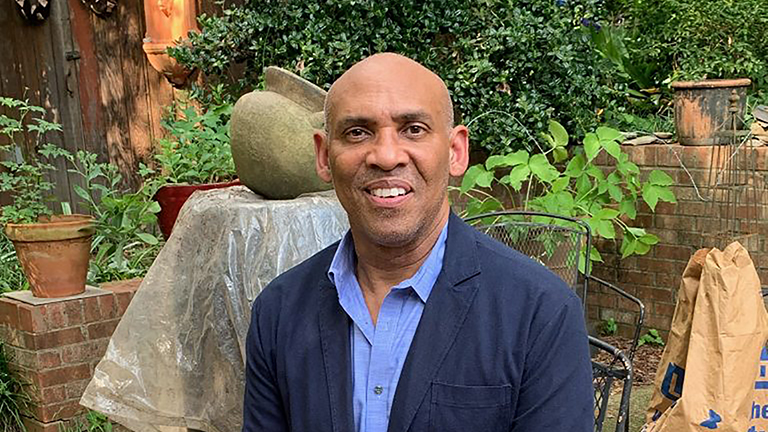 Color photograph of the head and torso of Richard Powell seated in an outdoor patio location
