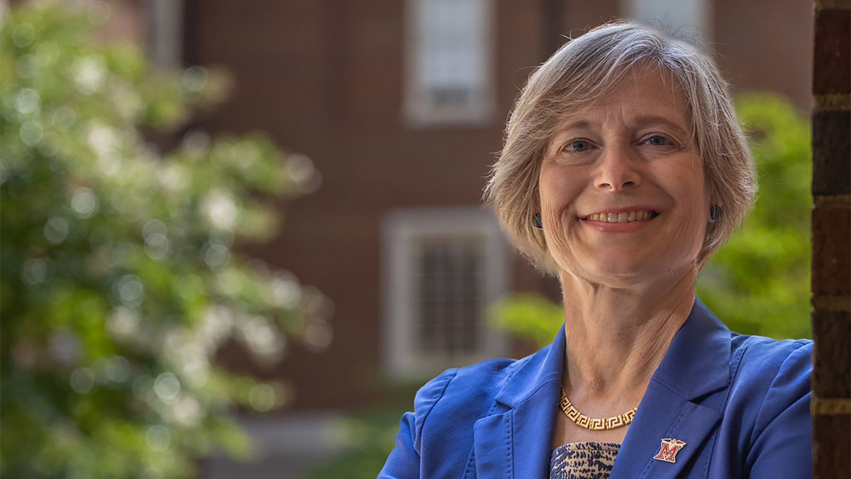 Color photo of the head and shoulders of a light skinned woman smiling at the camera