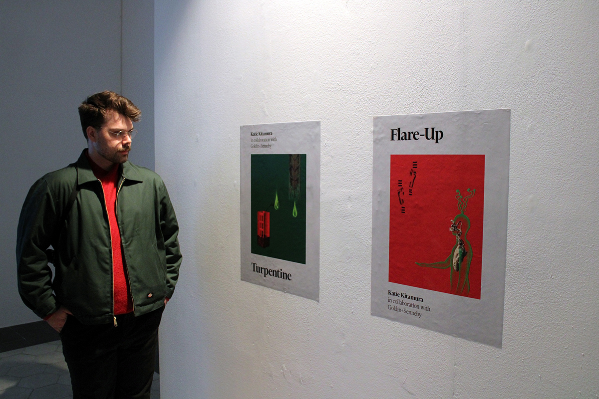 A man looking at two prints that mimic book covers that adhere to a white gallery wall