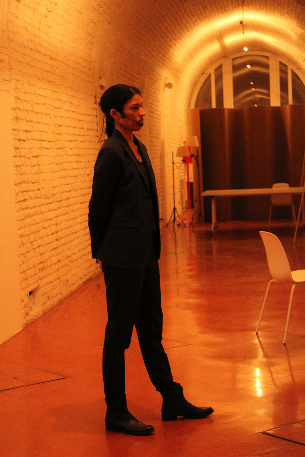 color photo of a Black woman standing in a orange-tinged cryptoporticus