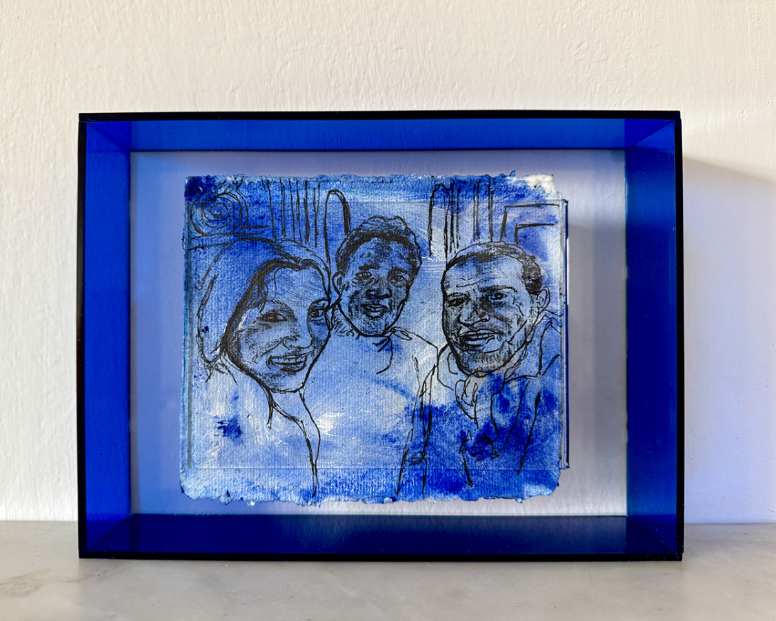 Photograph of a framed drawing of three faces in blue and black ink