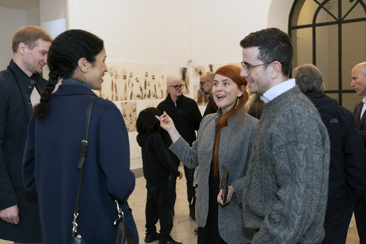 color photograph of eight or nine people in an art gallery talking to each other