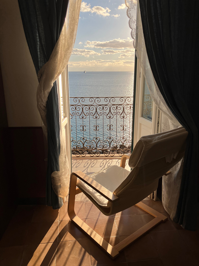 Photo of a chair curtains sky sea and railing