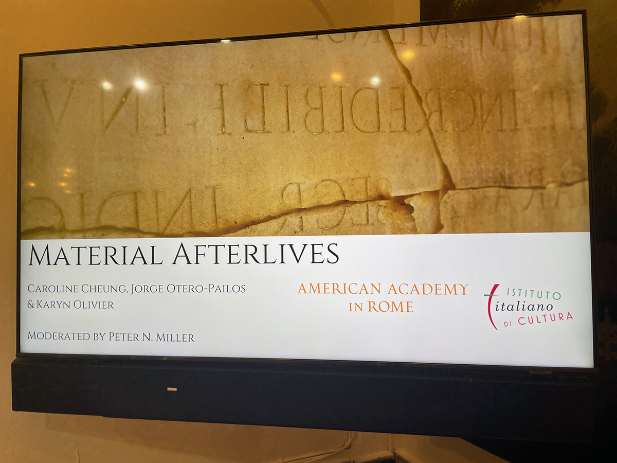 Color photo of a television screen depicting a graphically designed digital poster for a lecture