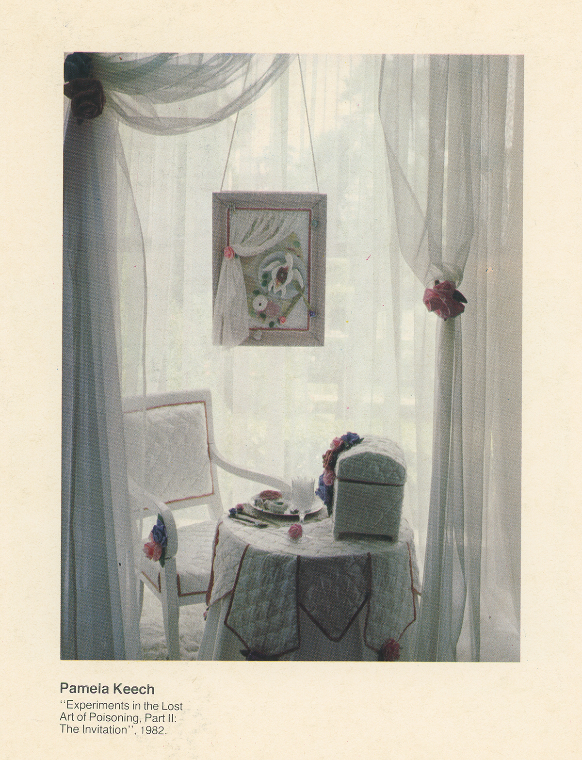 color scan of a book page with a photo of an art installation of a room with white curtains and a table, chair, and object with white quilted covers