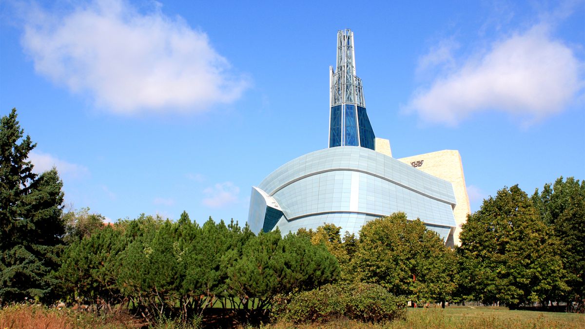 Color photograph of a building complex in a modern style, in front of a green garden or natural setting
