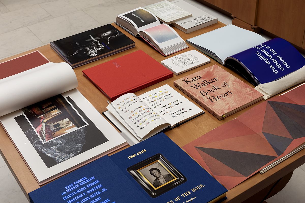 Color photo of eleven books of various sizes, some open to double page spreads, resting on a table