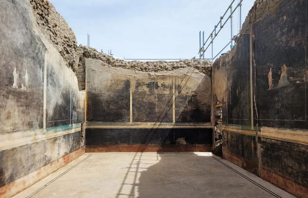 Color photo of an excavated room in Pompeii with black walls