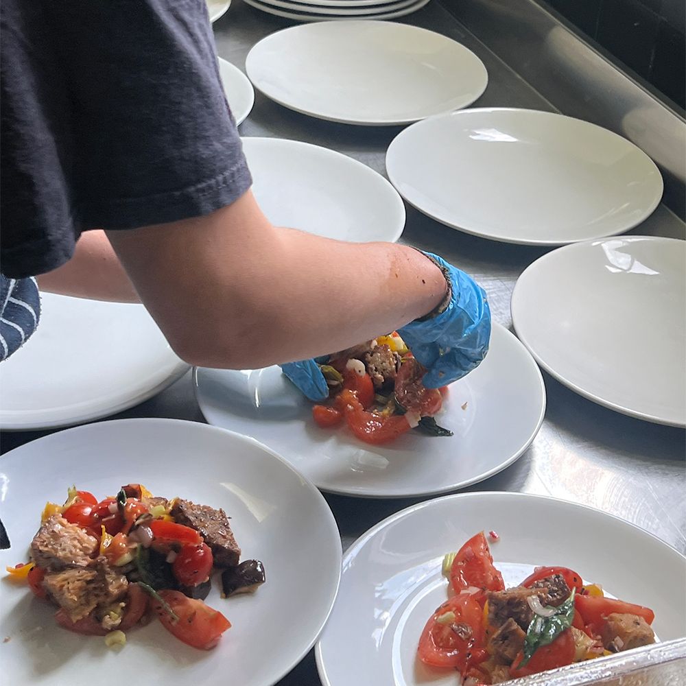 Color photo of a person plating dinner in kitchen