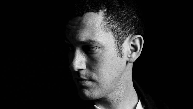 Black and white photograph of the head and torso of a light skinned man looking to his right