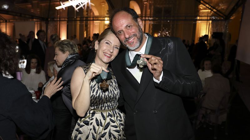 Color photograph of Paola Antonelli and Luca Guadagnino at the gala dinner, embracing and holding up the medals hung around their necks (photograph by Gerardo Gaetani)