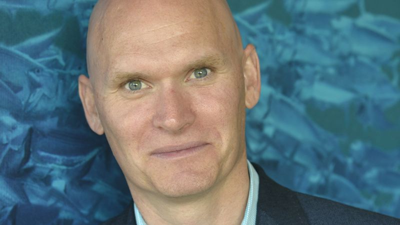 Color portrait of the head of Anthony Doerr against a blue background