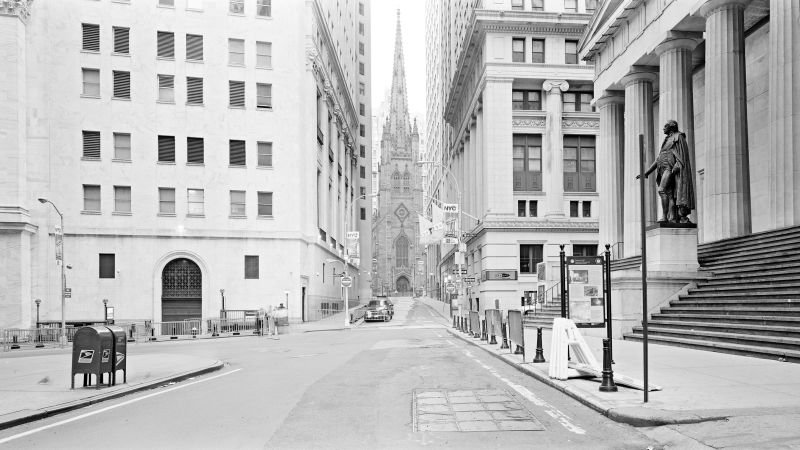 Black and white photograph of a depopulated Wall Street in the early morning, looking west at Trinity Church from the steps of Federal Hall