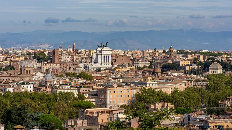 View of Rome showing a jumbled cityscape with mountains and sky in the distance