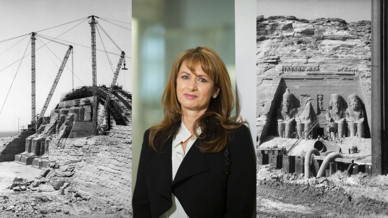 Composite of three images: color portrait of a light skinned, brown haired woman wearing a dark blazer and white shirt in the center, flanked by two black and white photographs of a crane moving a large stone Egyptian monument of a seated figure