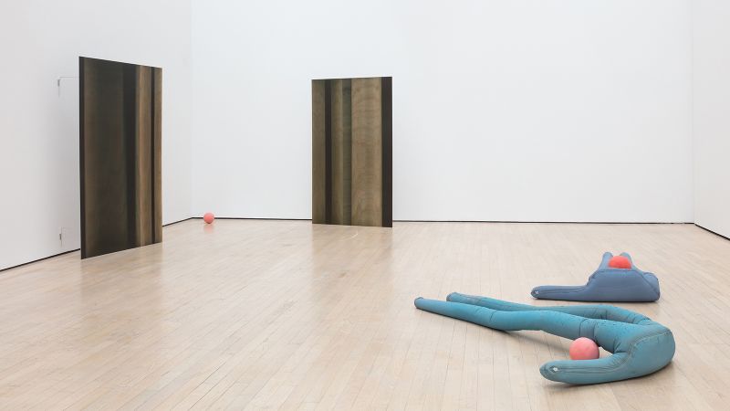 Color photograph showing the installation of a fabric sculpture and two wall panels by Sara Enrico in a brightly lit museum room interior