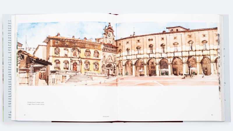 Color photograph of an open book showing a double page spread of a watercolor of a large building in Arezzo