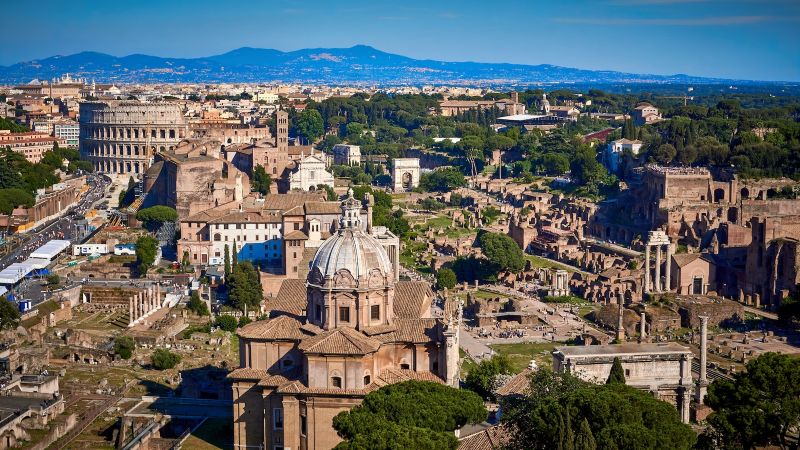 A aerial view of Rome, including the Forum and the Colosseum, with the Apennines behind 