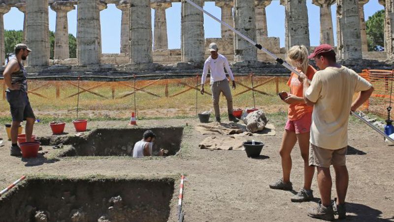 Color photograph of archaeologists working on a dig on a sunny day