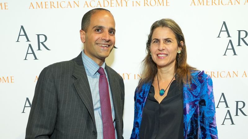 A man and a woman standing in front of a step and repeat