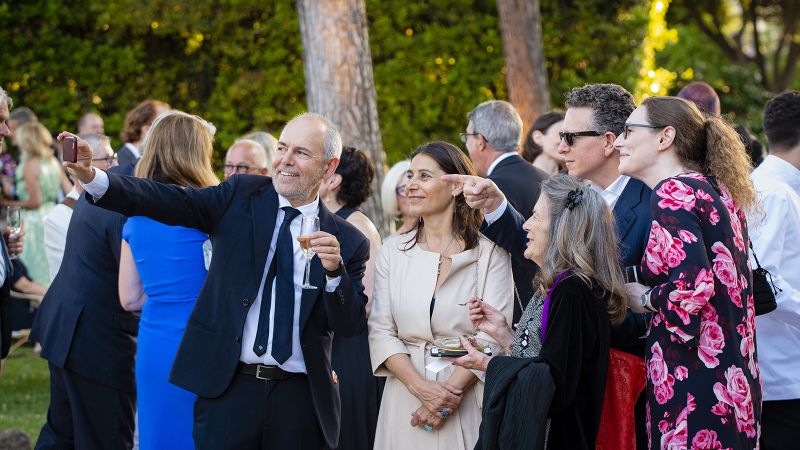 Color photograph of five light skinned people posing for a selfie in a Roman villa garden