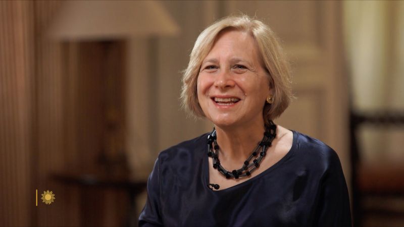 Color video still of a light skinned woman in an indoor location with blond hair talking to an offscreen interviewer