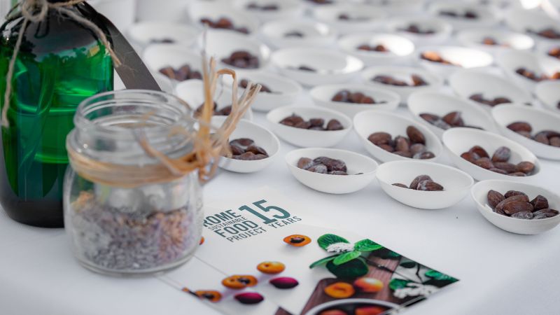 Color photograph of numerous bowls of seasoned almonds behind a printed paper brochure that says Rome Sustainable Food Project 15 Years