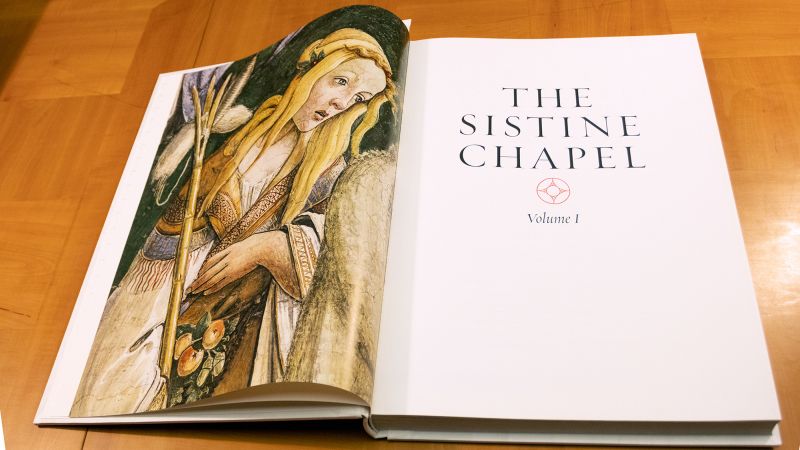 Color photograph of a large book on a table, opened to the title page on the right; a reproduction of a woman from a Renaissance fresco in on the left page